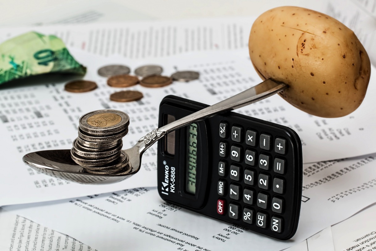 Coins on spoon with potato and calculator